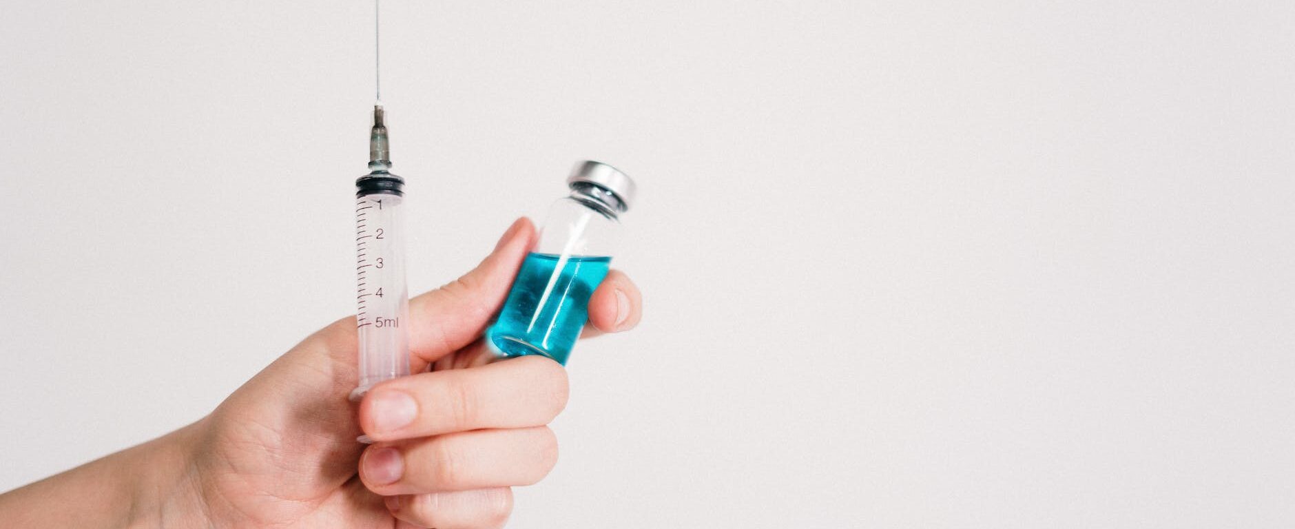person holding syringe and vaccine bottle